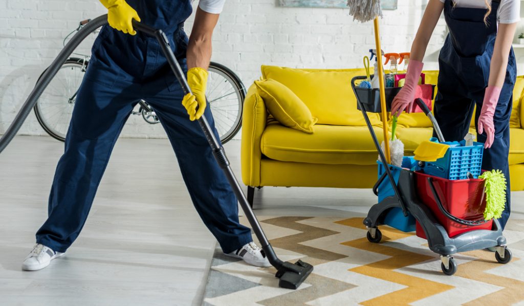 AdobeStock_©LIGHTFIELD STUDIOS_cropped view of cleaners in overalls cleaning apartment